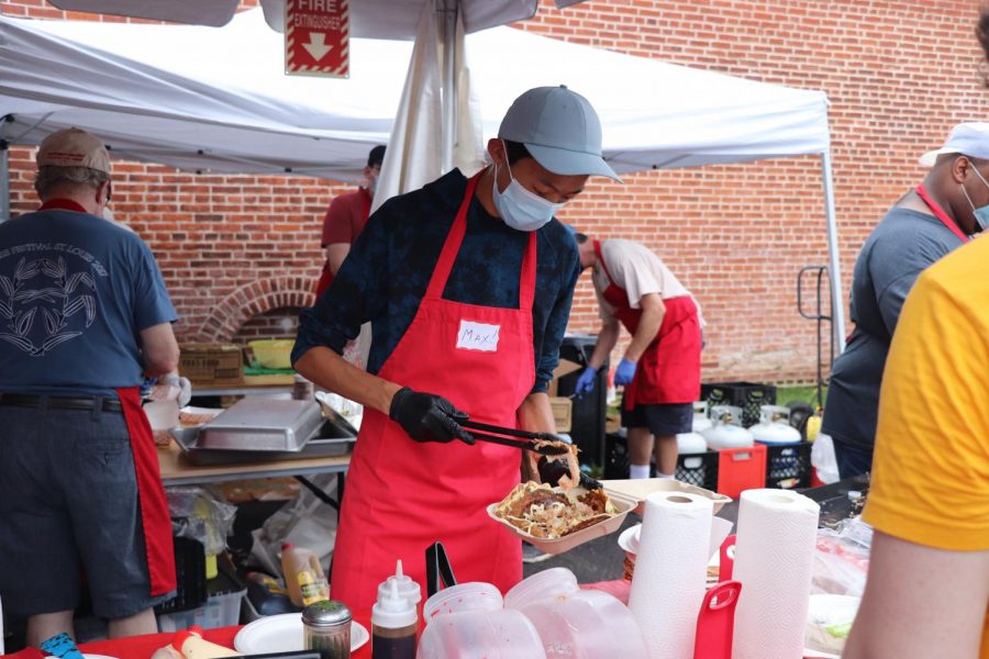 Max Yang helps cooks at the Seinen Kai booth put toppings on Okonomiyaki for the customers. 