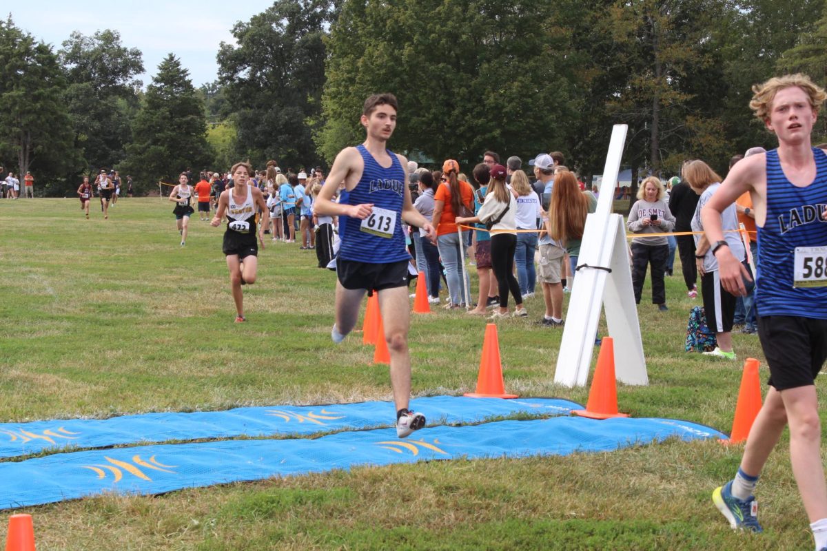 Mikhail Vinch (12) and Cooper Buxner (9) finish the junior varsity boys race.