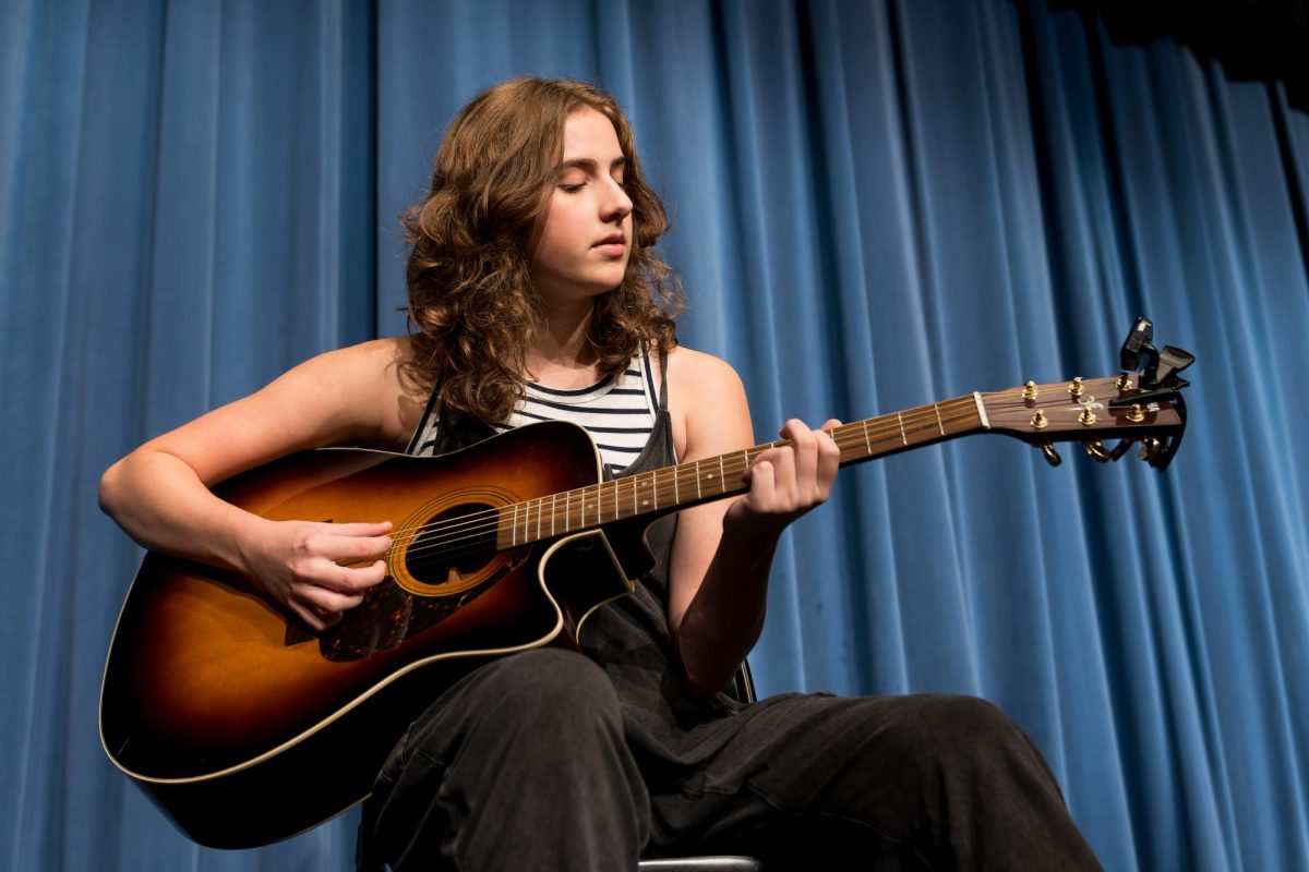 Norah Murphy (10) plays her guitar in the theater Sept. 21. Murphy started playing guitar and writing songs in fourth grade. “I started because I’ve always wanted to do it after singing songs. It’s just been better now because I think I’m getting better at it,” Murphy said.
