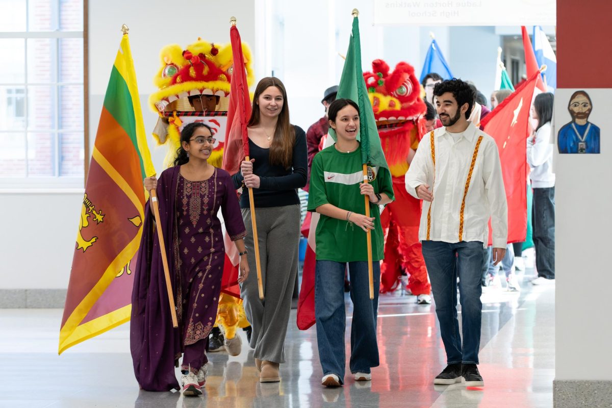 Sara Rohatgi (11), Gia Grillo (11), Alexandra Tsygankov (11) and Luca Pinon-Dickey (11) walk through the hallway holding flags of different countries. The parade took place during seminar Feb. 5. “I like seeing all of the countries come together in one event,” Grillo said.