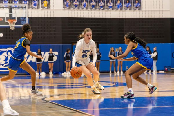 Chip Calvert
(11) dribbles to
escape Burroughs
defender. The
basketball team
has played in 17
regular season
games. “We have
found a nice
balance of pushing
each other to
get better and
helping,” Brennan
said.