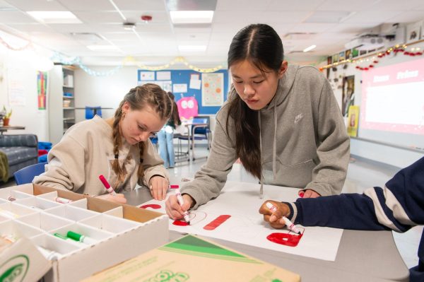 Claire Yates (9) and Serenity Xu (9) decorate posters for the Valentine’s Day fundraiser. FemCo held a meeting with members Jan. 23 to create decorations. “I’m looking forward to being a part of a club that’s doing a fundraiser,” Yates said. 
